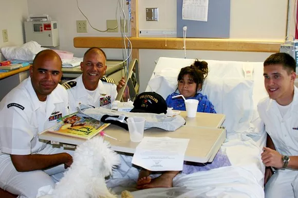 병원 침대에 누워 있는 어린 소녀와 세 명의 군인