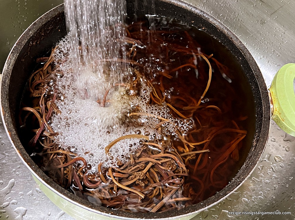 삶아진 고사리를 흐르는 물에 헹궈주는 사진