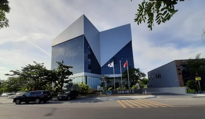 현대적인 오피스 빌딩, 기하학적 건축물, 유리 외관, 화창한 날, 앞차, 깃발 흔들기, 나무와 조경, 현대적인 디자인, 도시 환경, 맑은 하늘, 전문적인 기업 환경, 주다낭 대한민국 총영사관