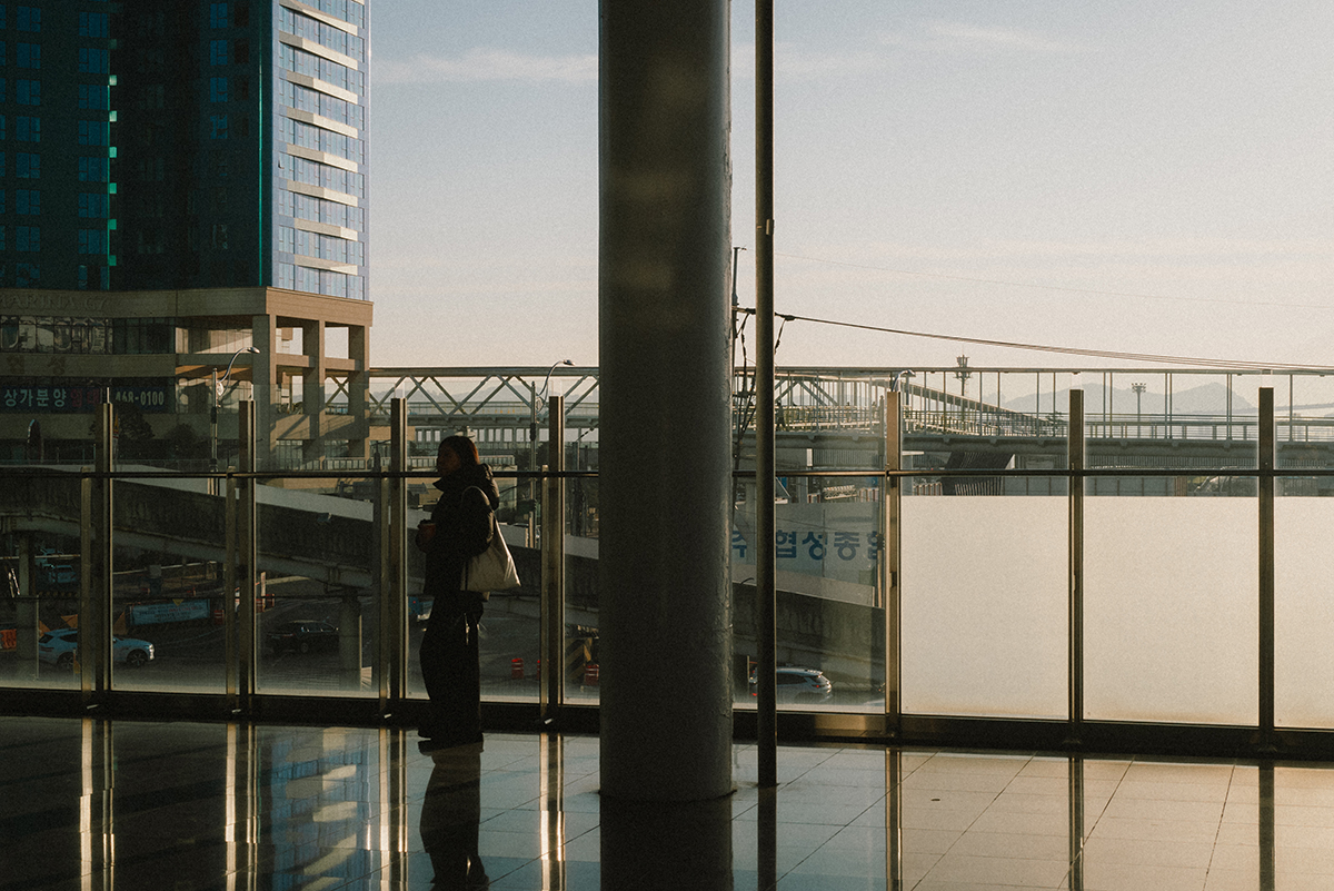 난간에 여자가 서있고 그 여자의 대각선으로 해가 떠오르는 빛이 비춘다. 덕분에 여자는 실루엣으로 표현되어 있다.