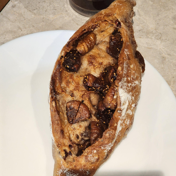 겉이 바삭하고 고소한 곡물 빵, 속에는 잘게 썬 무화과와 견과류가 가득 들어 있는 바게트 스타일의 빵