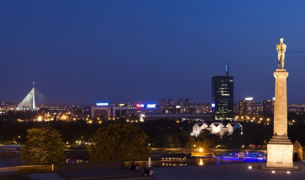 화려한 조명이 켜진 베오그라드 사바 강변의 유람선과 언덕 위 구시가지 건물의 야경 전경