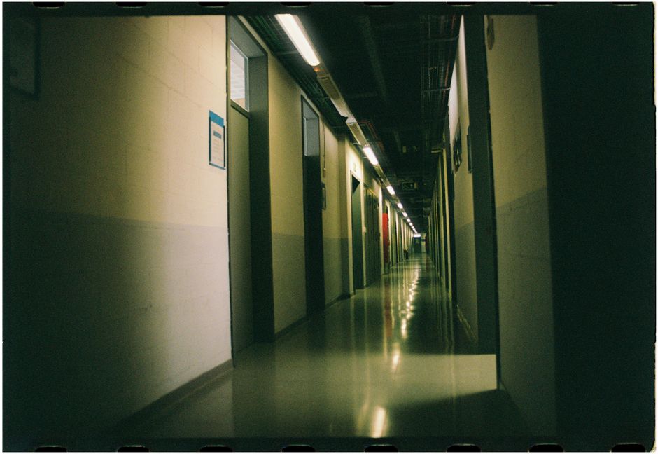 Dark and industrial corridor with dim lighting and perspective view captured with analog photography.
