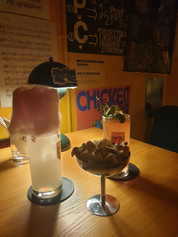 기본 안주 강냉이와 칵테일 두개, 솜사탕이 올라가 있는 칵테일이 끼다.