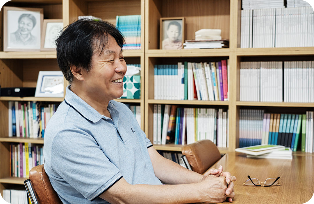 #본인의 서고 안의 테이블 의자에 앉아 안경을 벗고 인터뷰 하고있는 이재무 시인