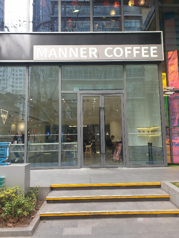 유리로 되어있는 매너 커피 전면. 간판은 회색 메탈