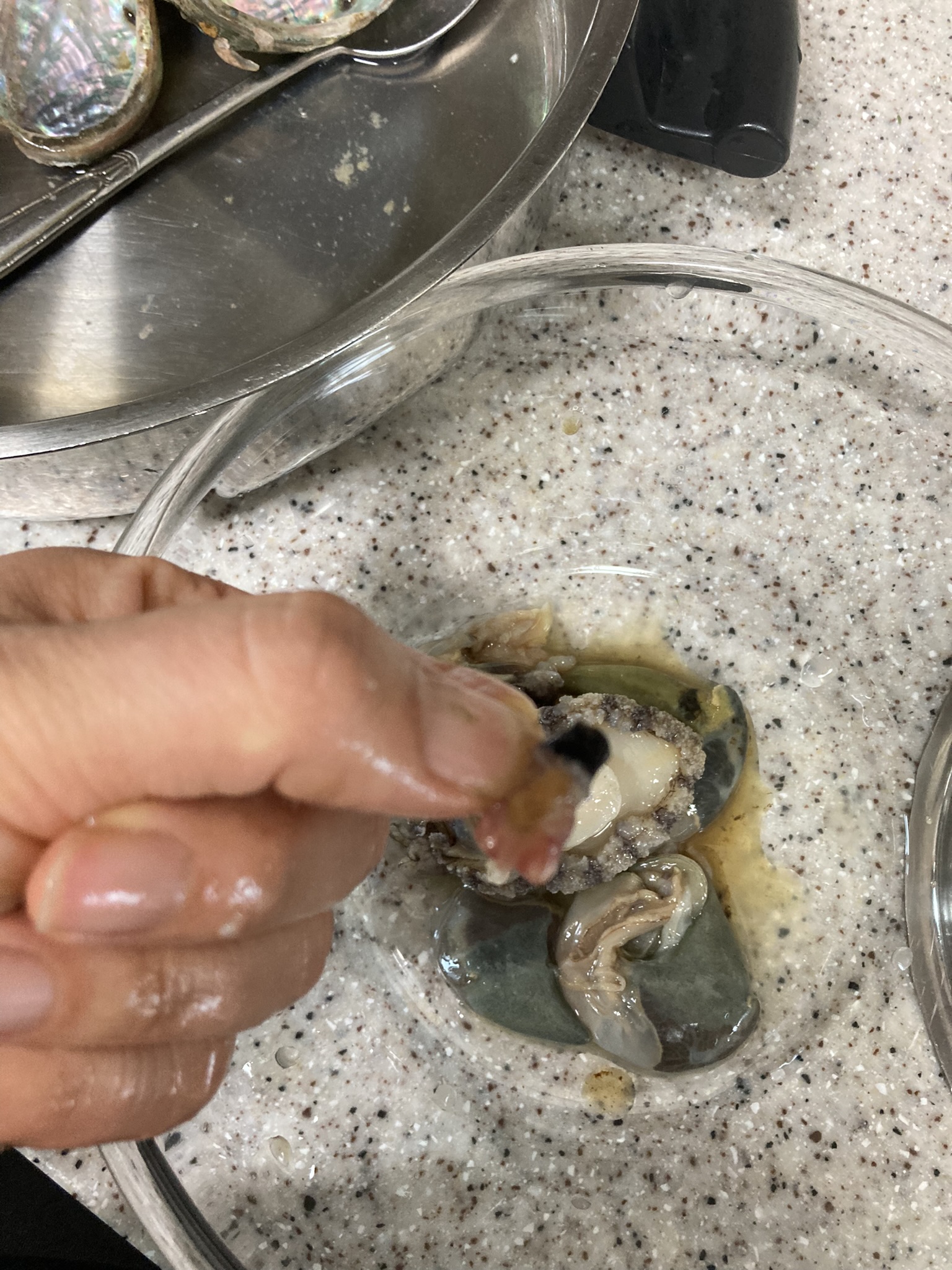 검은 입 부분을 잡고 전복 내장을 손으로 떼어내는 장면