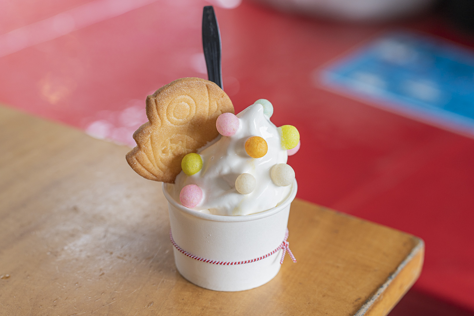 Mamemono to Taiyaki, Arashiyama: soft serve in a paper cup with a fish-shaped wafer and small colorful toppings.