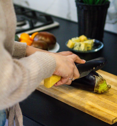 가지볶음을 만들기 위해, 여성이 주방에서 도마 위에 놓인 가지를 칼로 자르는 모습