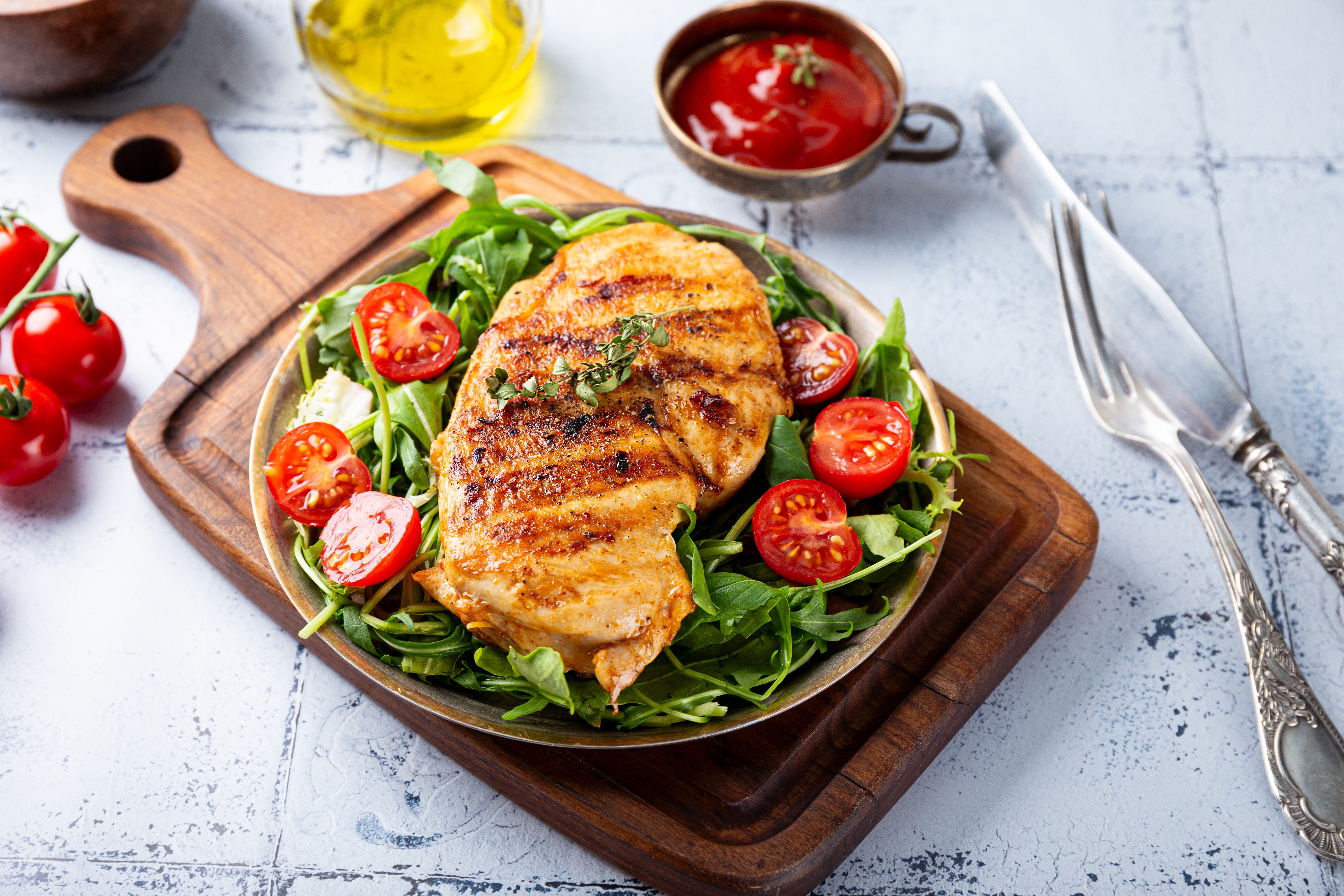 신선한 채소와 방울토마토 위에 구운 닭가슴살이 올려진 건강한 외식 메뉴 한 접시