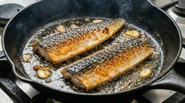 프라이펜에 잘 손질된 고등어 2마리가 구워지고 있음.