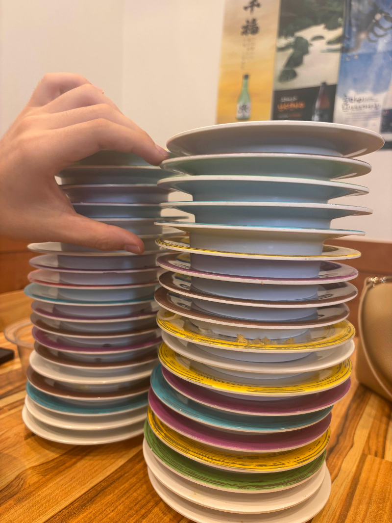 ๋ค์ํ ์์ ํ์ ์ด๋ฐฅ ์ ์๊ฐ ์์ธ ๋ชจ์ต
A tall stack of assorted K-sushi plates after dining