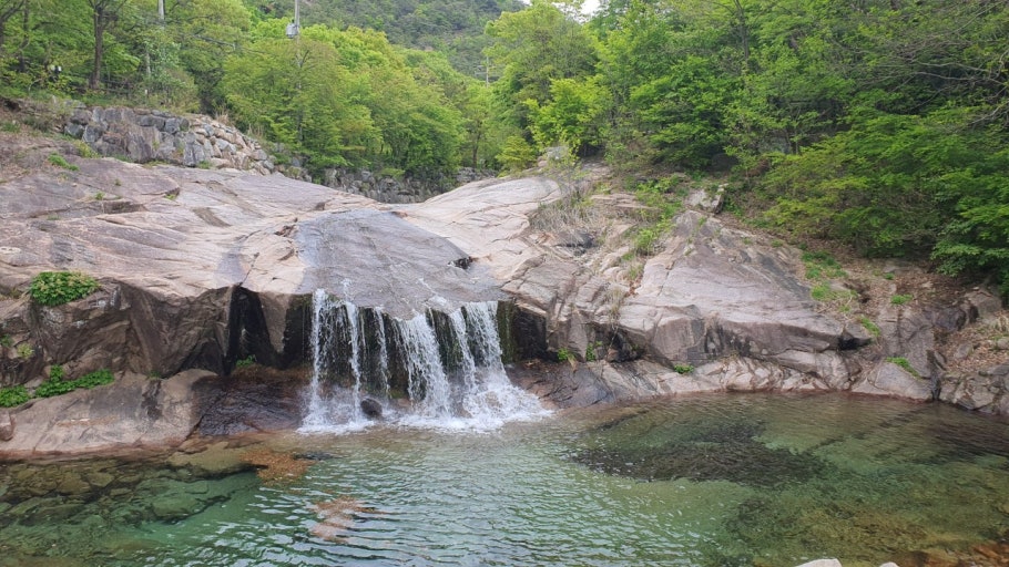 송추계곡의 넓은 암반 위로 흐르는 자연 폭포와 맑은 에메랄드빛 계곡수 풍경