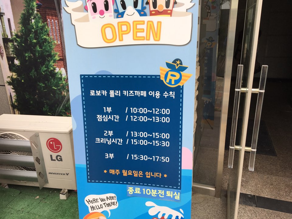 키즈카페 운영 시간 안내판. 1부(10:00~12:00), 2부(13:00~15:00), 3부(15:30~17:50) 이용 시간 및 월요일 휴무 명시.