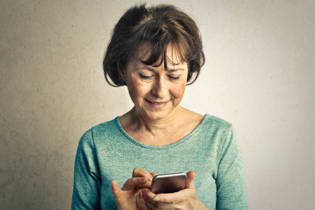 스마트폰을 보며 부드럽게 웃고 있는 중년 여성