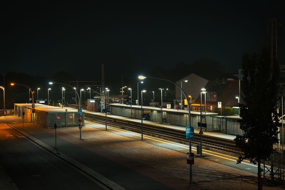 Night view of an illuminated train station platform, showcasing urban solitude and modern lighting.