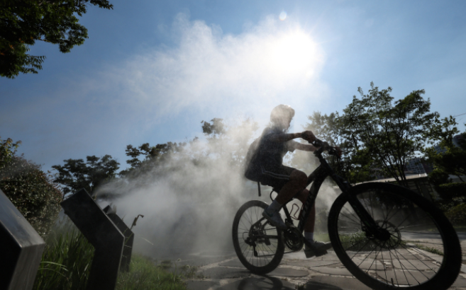 대구 지역에 폭염주의보가 발효된 18일 대구 중구 김광석다시그리기길 인근에 설치된 쿨링포그(안개형 냉각수)에서 한 학생이 자전거를 타고 이동하고 있다..