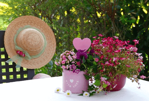 하얀 탁자 위에 빨간 꽃이 가득 담긴 분홍화분과 빨간 화분이 있다. 의자에는 여인의 챙이 넓은 갈색모자가 있고, 분홍화분에는 사랑이란 글자가 영어로 적혀있다.