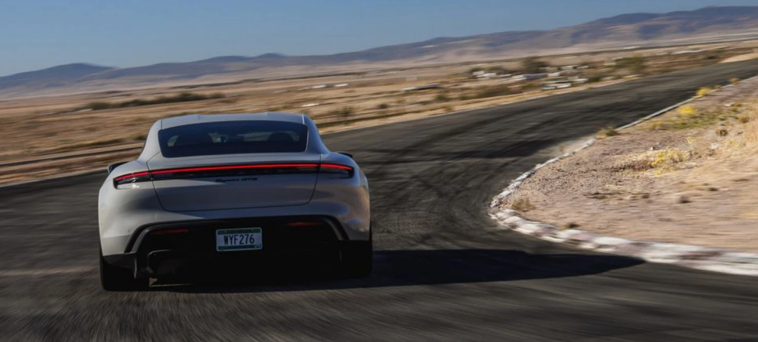 회색의-포르쉐-타이칸-GTS가-사막-도로를-달리고-있으며-정후방의-차량-모습이-보이고-있다