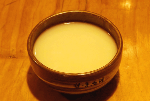 갈색 그릇에 묽은 막걸리가 가득하다.