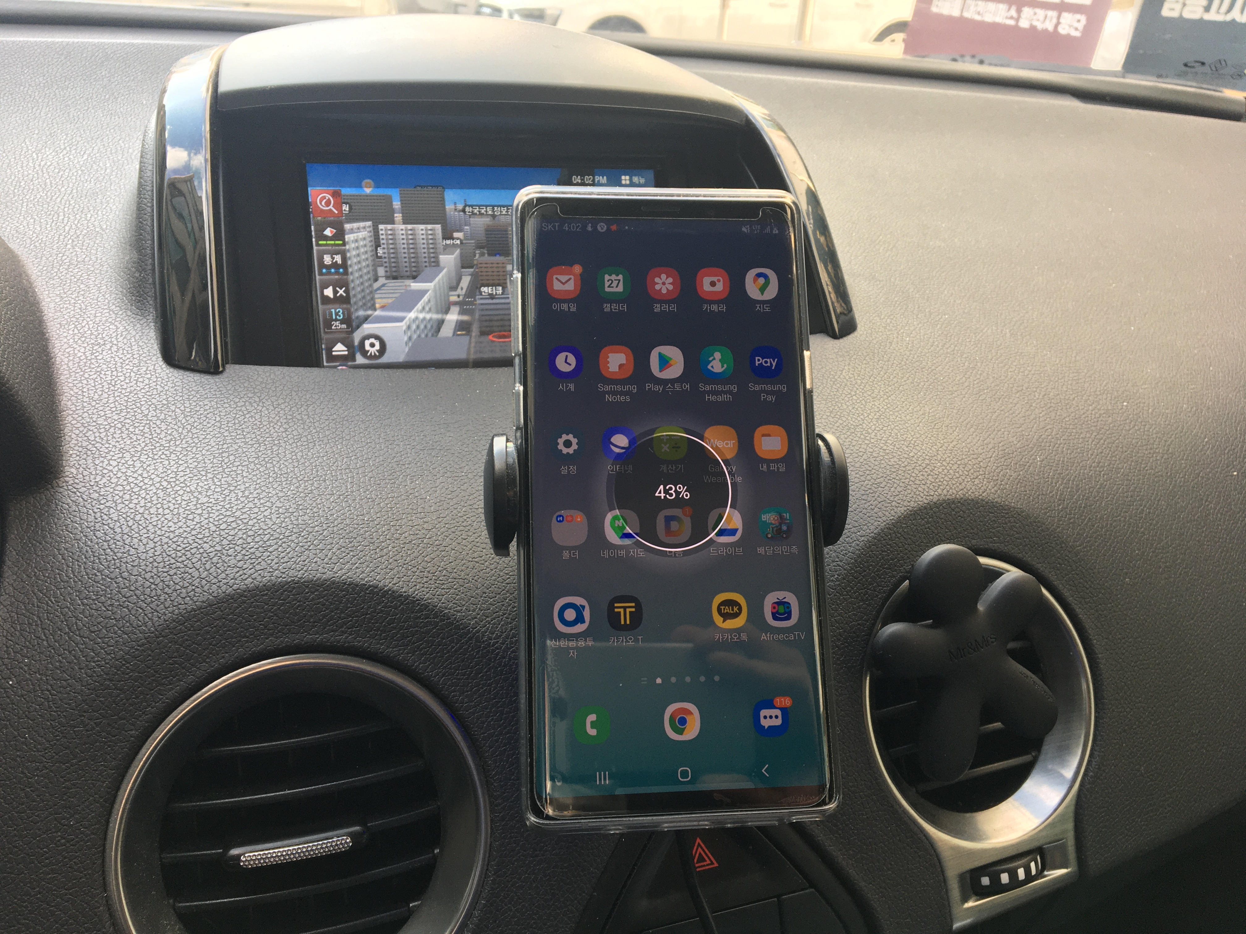 차량 대시보드에 부착된 신지모루 오그랩 거치대에 갤럭시 노트9이 장착되어 충전 중인 모습
