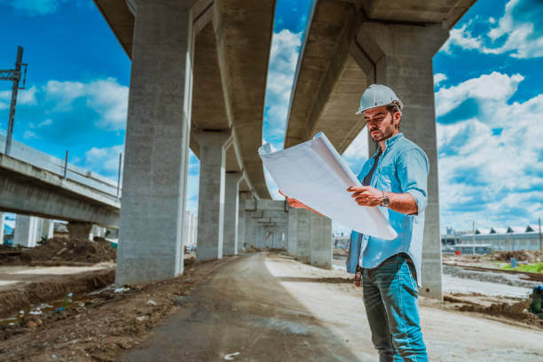 교량 설계 도면을 살펴보며 현장을 점검하는 토목기사의 모습