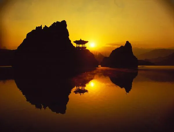 “단양 도담삼봉의 아침. 세 개의 돌봉우리가 강 위에서 솟아오르고, 여행자가 나무 덱 위를 걷고 있는 평화로운 풍경.”