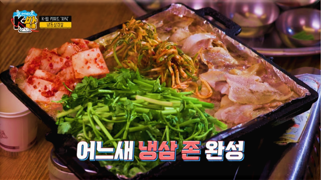불판-위에-삼겹살과-미나리,-김치와-파채가-가득-올려진-모습