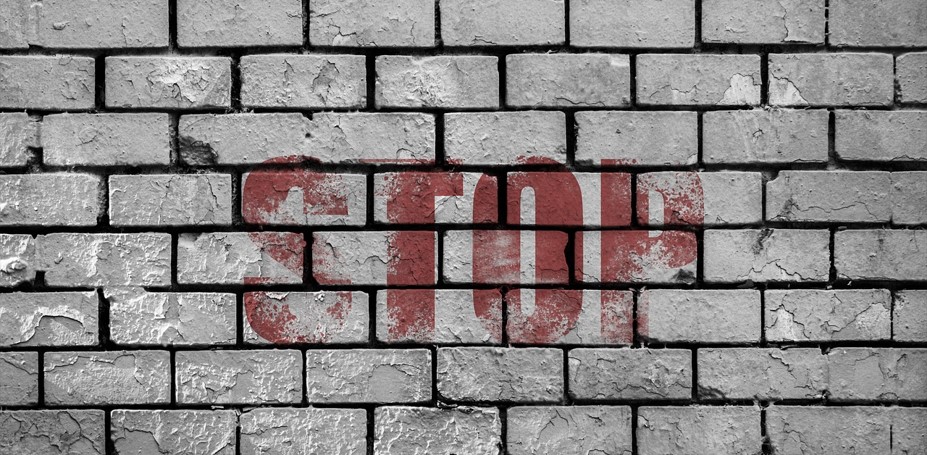 벽돌로 쌓아 올린 벽에 붉고 굵은 글씨로 영어 'STOP'이라는 글자가 쓰여 있는 사진