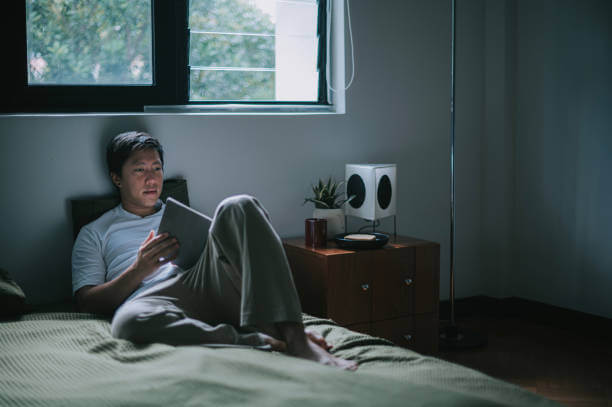 취침전 침대에서 디지털 기기를 들여다보는 남성