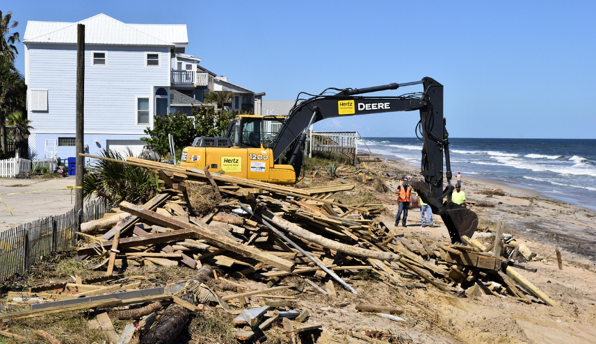 Excavator clearing up aftermath of hurricane near the beach