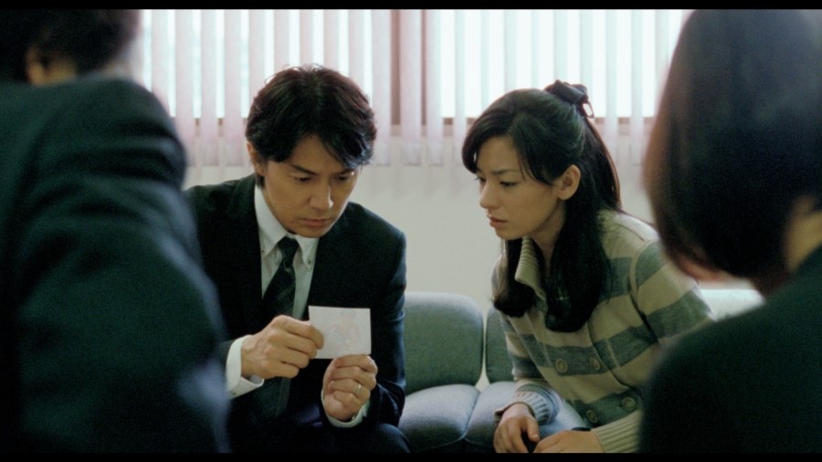 영화 그렇게 아버지가 된다 속 바뀐 아이의 사진을 보고 있는 주인공