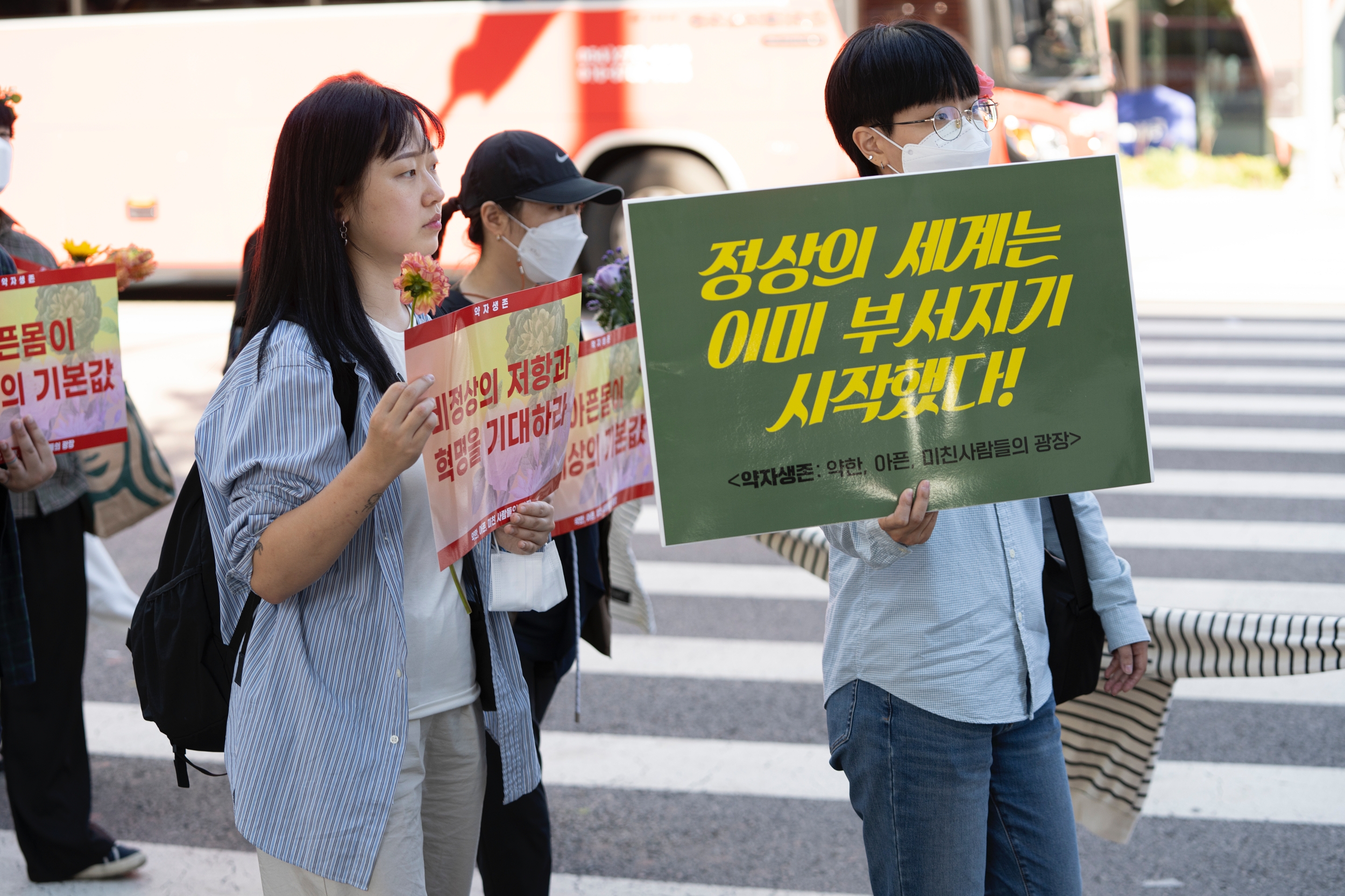 시민이 '정상의 세계는 이미 부서지기 시작했다!'라는 피켓을 들고 행진하고 있다.
