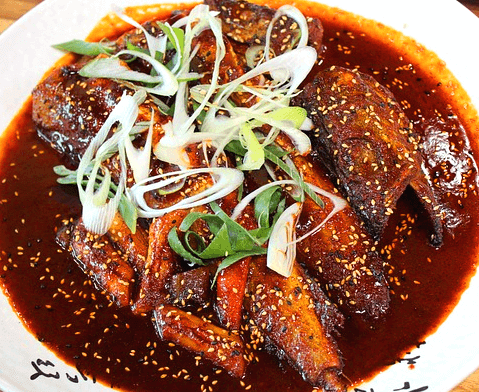 하얀 접시에 간장에 조린 코다리조림이 있다. 살코기가 가득한 생선조림이며 위에는 잘린 대파가 가득하다.