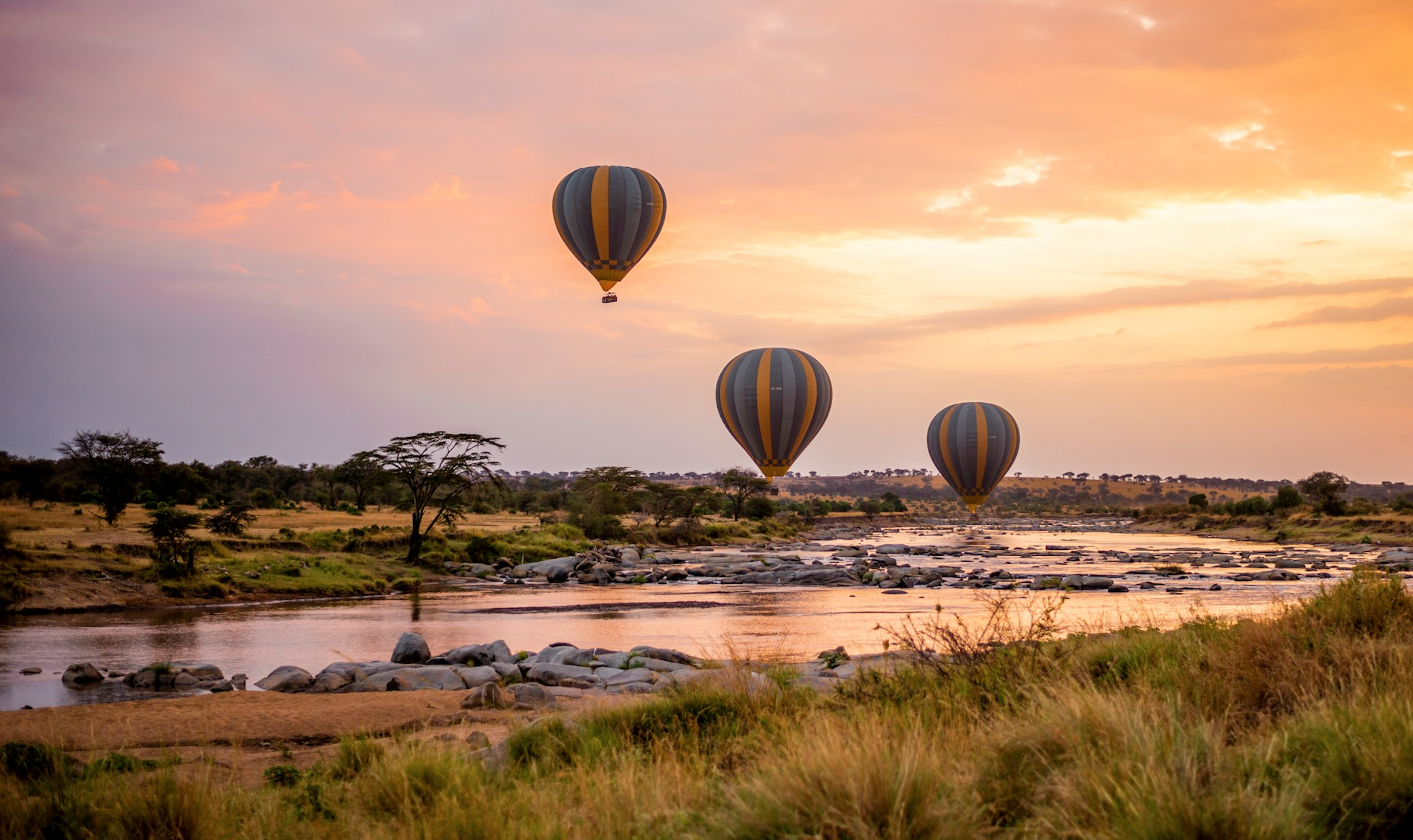 Hot Air Balloons Floating Over a River in the Serengeti at Sunrise
