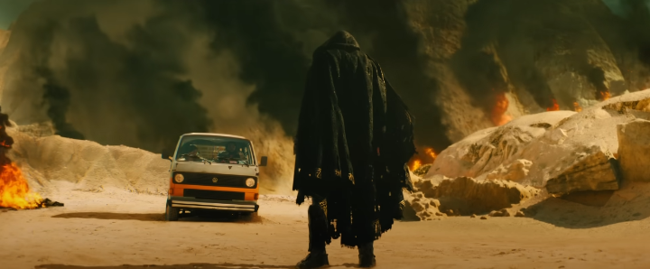 엄청난폭발연기속에서있는검은망토를걸친남성의뒷모습