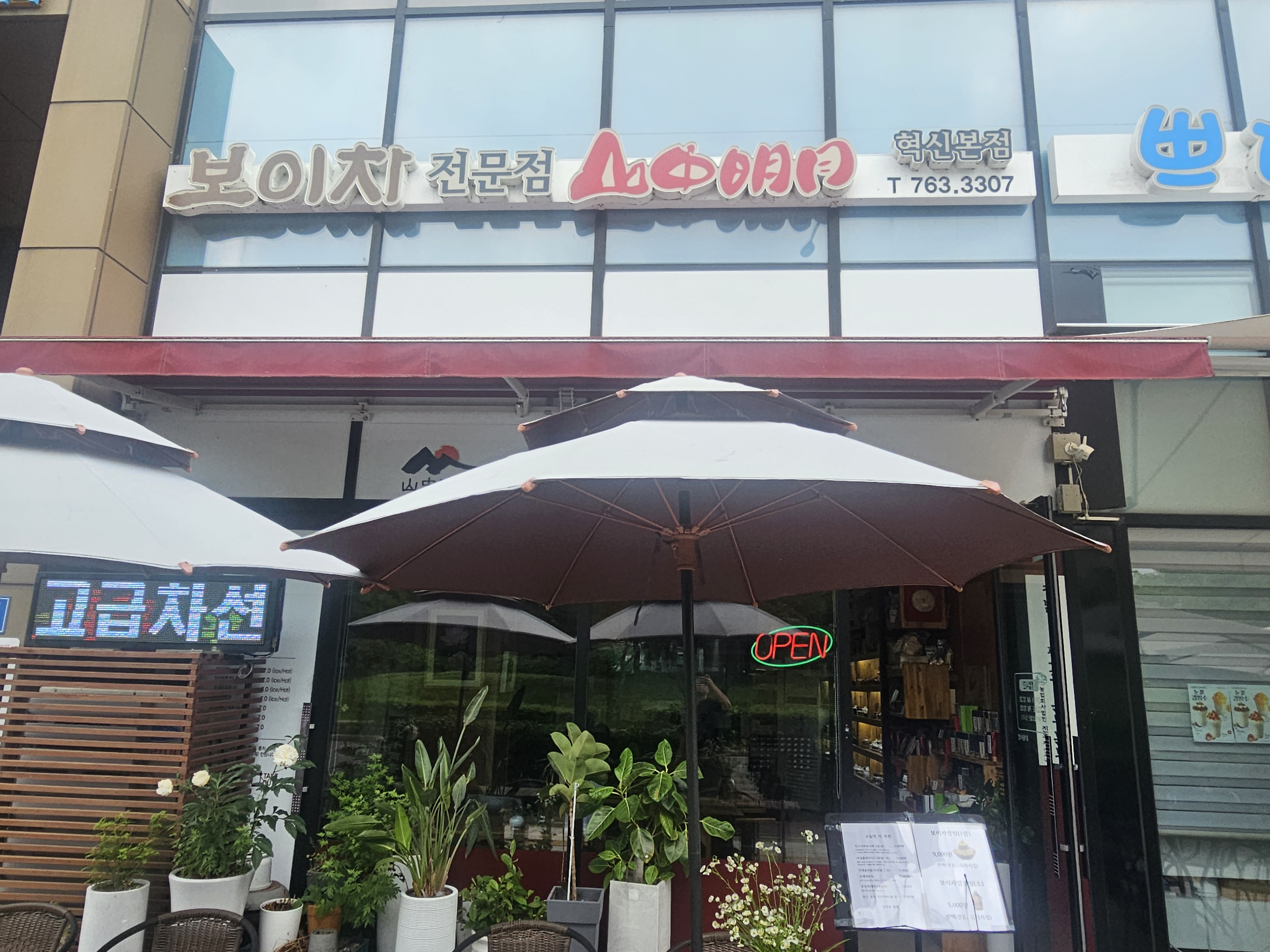 보이차 전문점 산중명월 외관 — 혁신본점 간판과 야외 파라솔 좌석