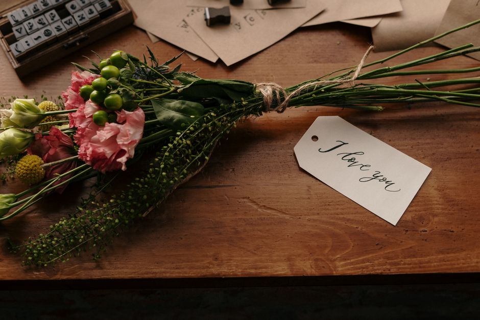 A beautiful bouquet with a heartfelt 'I love you' note on a rustic wooden desk, captured in warm tones.