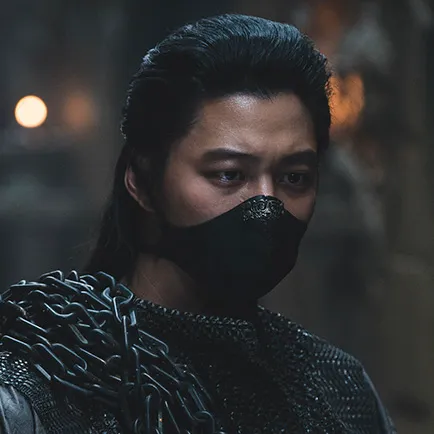 머리를 뒤로 묶은 30대 남성이 검은 쇠사슬을 두르고 검은 마스크를 쓰고 서 있는 아라문의 검 양차 캐릭터