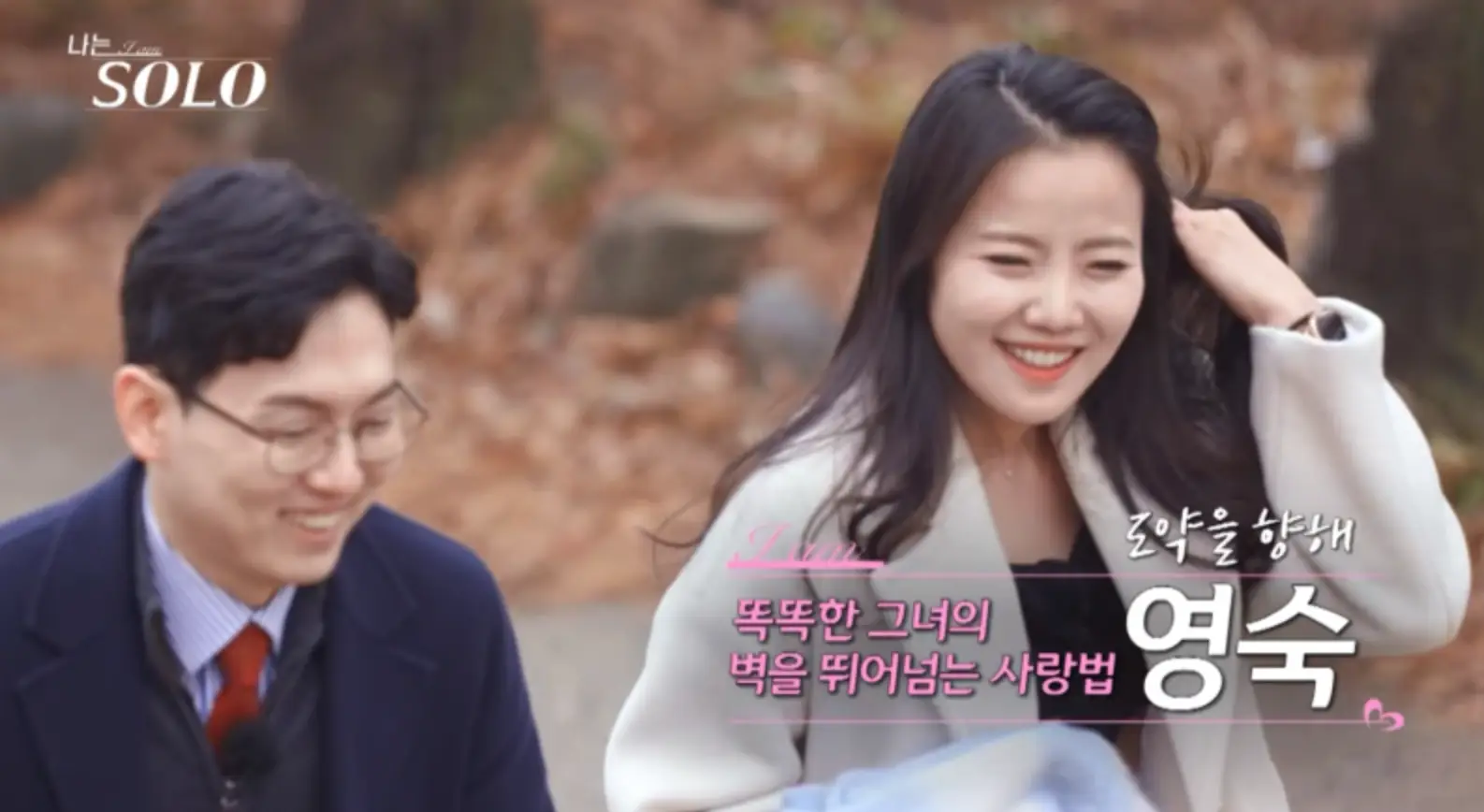 나는솔로-흰정장입여자가 긴머리를 늘어뜨린채 웃으며 말하고 좌측 웃으며 파란 정장을 입고 웃는 남자