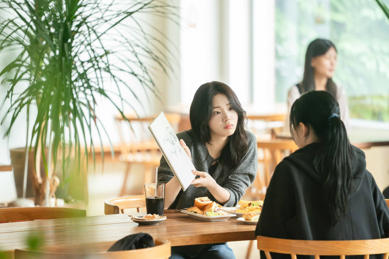 재원을 그린 스케치북을 친구에게 보여주는 서윤