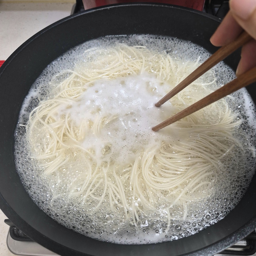 끓는 물에서 젓가락으로 풀어가며 소면을 삶는 모습