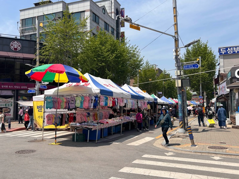 K-Yongmun 5-Day Market street view with baby clothes stalls.