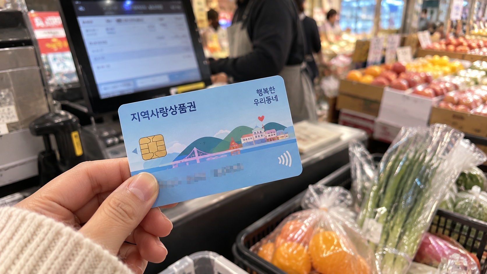 동네 마트에서 지역사랑상품권 카드를 들고 채소와 과일을 구매하려는 장보기 모습