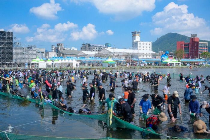탐진강 물속에서 황금물고기 잡기 체험을 즐기는 참가자들로 가득 찬 장흥 물축제 현장