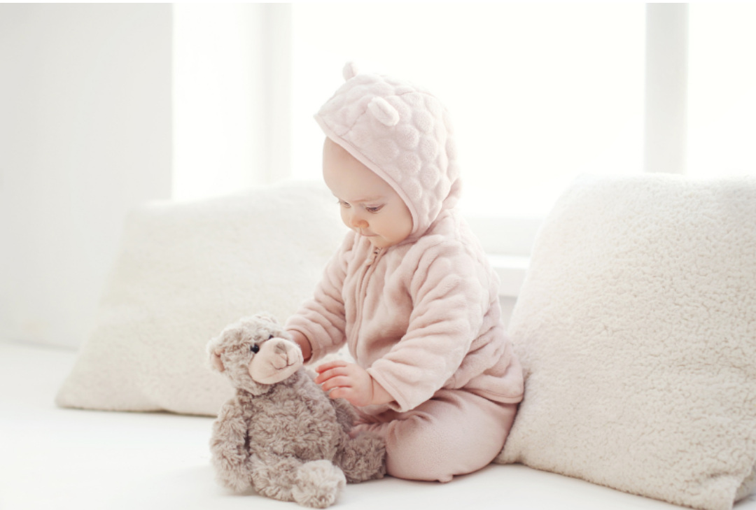 아기가 곰돌이 인형을 가지고 놀고 있다.