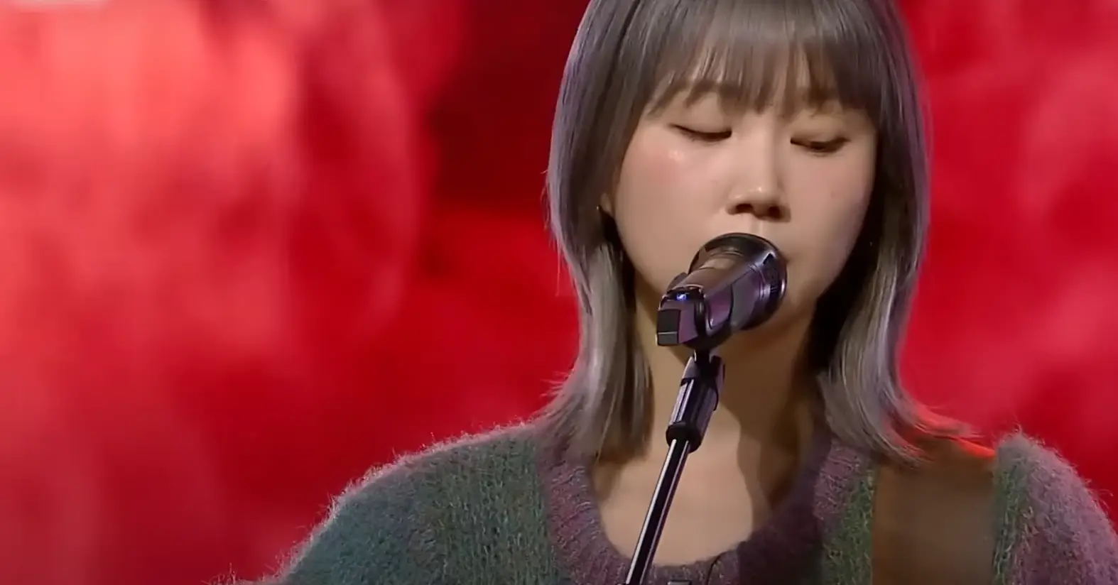 싱어게인 3- 분홍색을 배경으로 키타를 치며 단발머리를 늘어뜨린채 진지하게 노래부르는 60호