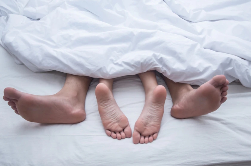 침대에 누워 이불을 덮고 다리만 나와 있는 두사람