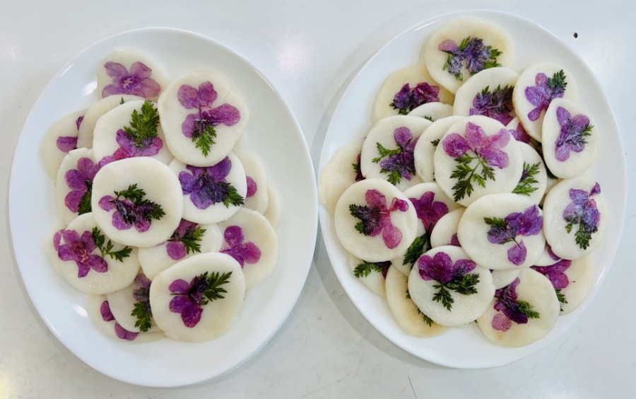 야생에서 채취를 한 진달래꽃을 쌀가루로 만든 전에 붙여서 같이 익혀서 만든 화전을 흰색 바닥 위에 희고 동그란 접시 2개에 가득 담아두고 찍은 사진