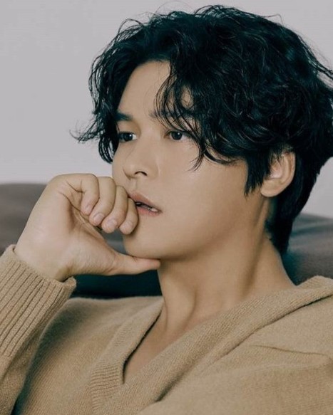 배우-이장우-결혼-이장우가-베이지-니트를-입고-오른손으로-턱을-괴고-있다.
